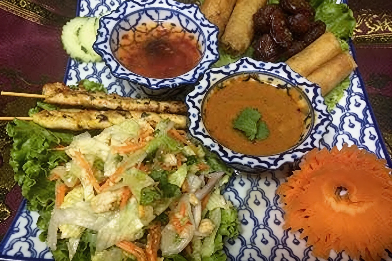 Assortiment d'entrées sur un plateau bleu et blanc, coupelles de sauce, sur une nappe violette