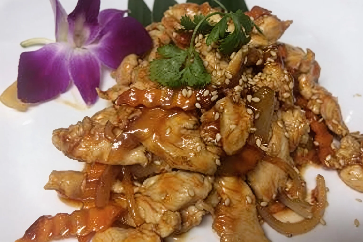 Poulet sauté dans une assiette blanche, orchidée violette